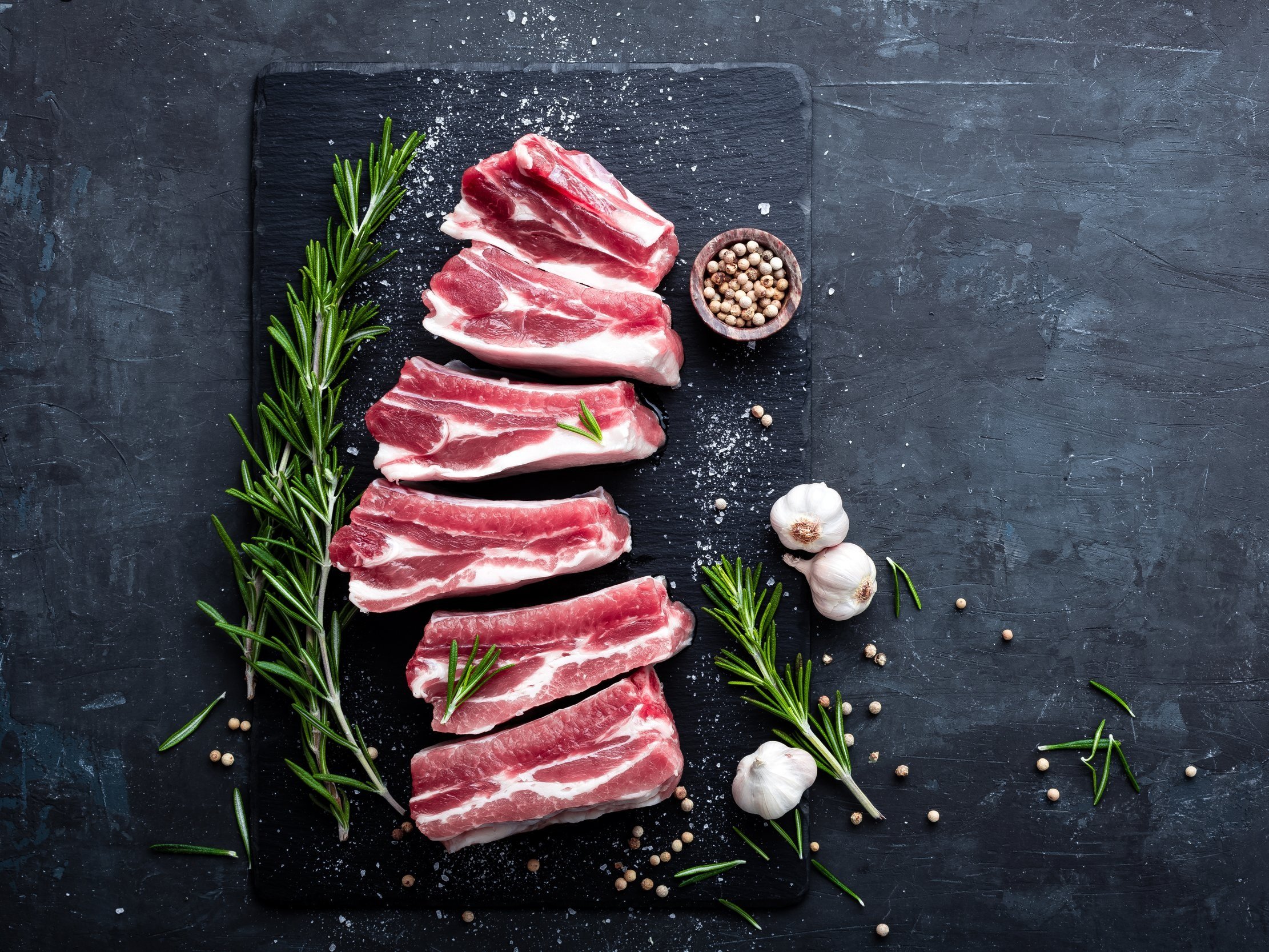 Idaho+Pasture+Pig Fresh farm eggs in a carton featuring various colors, including brown, white, and cream, resting on a rustic wooden surface. Ideal for cooking and baking.